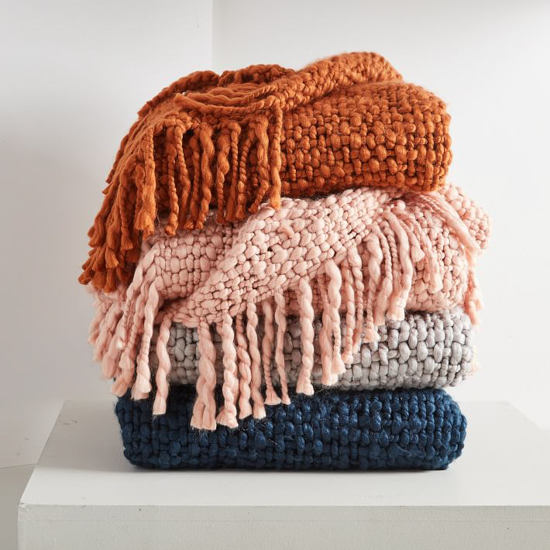 Stack of four colorful fringed throw blankets