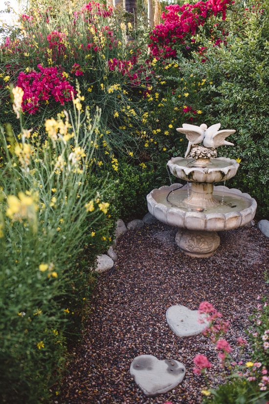 Water fountain with birds on the top and heart shaped stepping stones amongst pea gravel. 