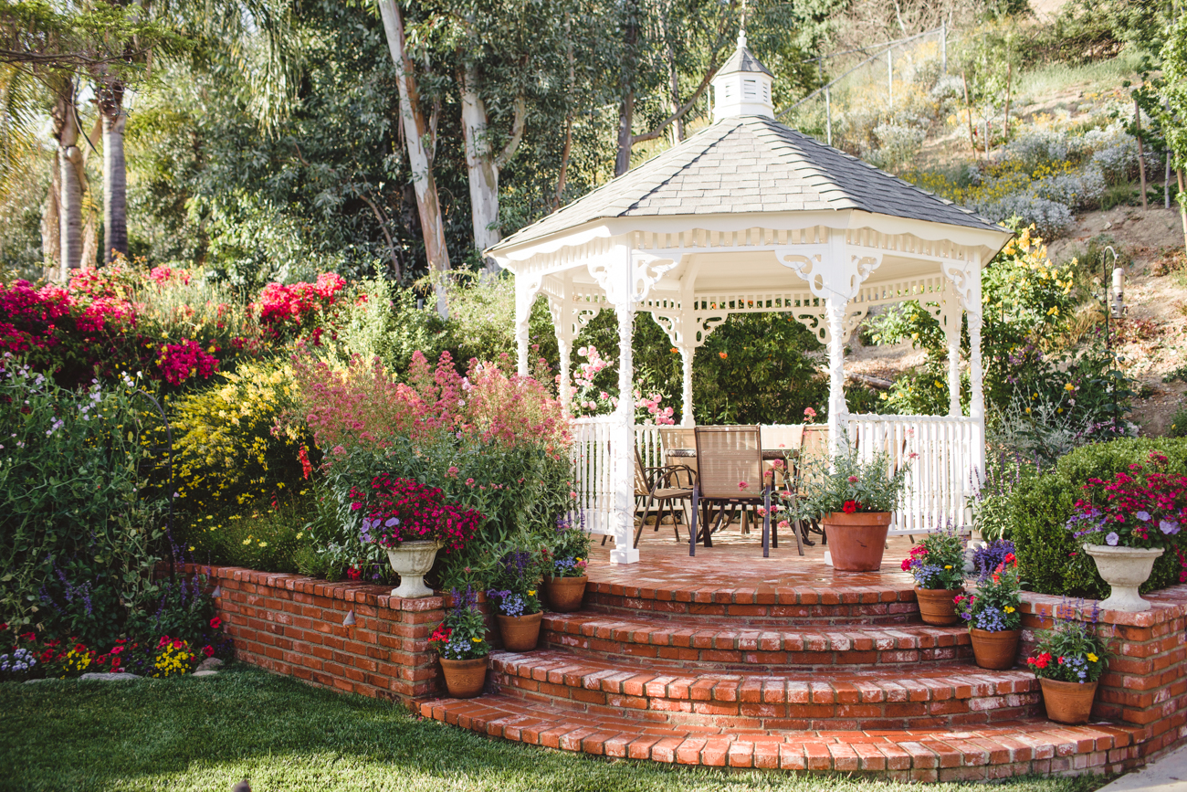Brick steps leading up to a white gazebo surrounded by a blossoming garden.