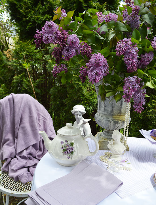 lovely garden table with an urn full of dark purple lilacs