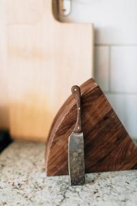 marbled countertops with cutting board in the background, featuring a walnut cutting wedge and handmade cheese knife.