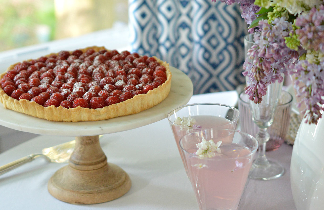 raspberry tart and pink lemonade on a pretty table with lilacs