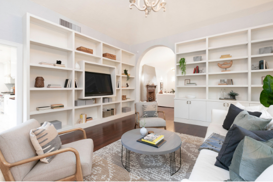 Floor-to-ceiling white bookshelves sit on polished wood floors.