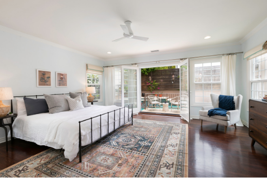 A large bed sits in an iron frame on top of a sprawling Aztec-printed area rug.