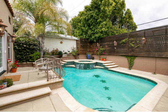 A turquoise-tiled pool and spa creeps across the enclosed backyard.