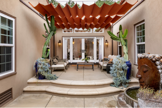 A burnt orange canopy hangs over wooden furniture and desert plants.