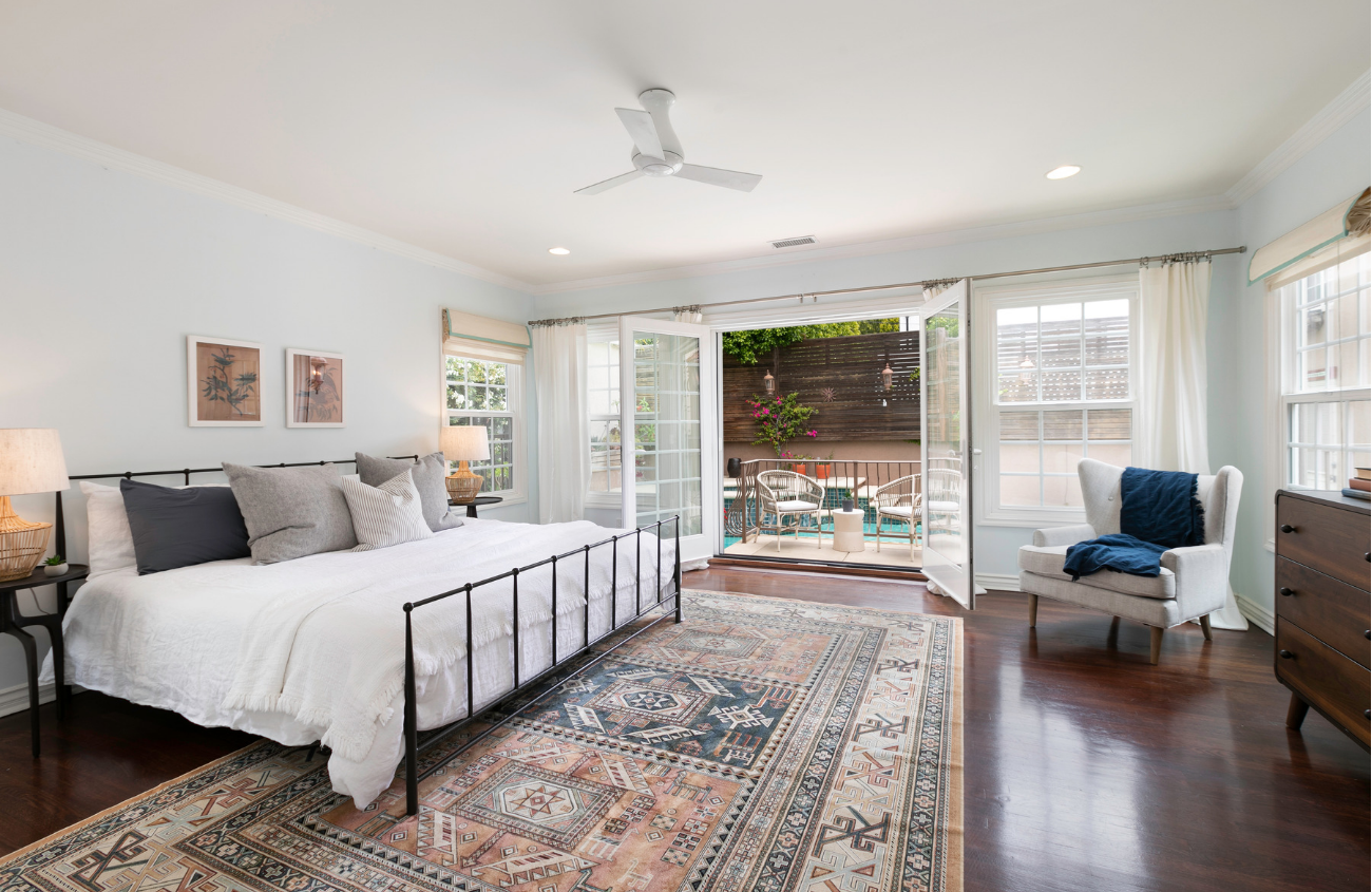 The cottage’s master bedroom hints at its Spanish roots with an Aztec-printed rug and iron bed frame, and French doors open to the backyard’s sparkling turquoise pool.