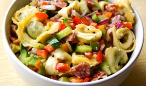 Tortellini and salami salad sits in a bowl
