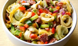 Tortellini and salami salad sits in a bowl