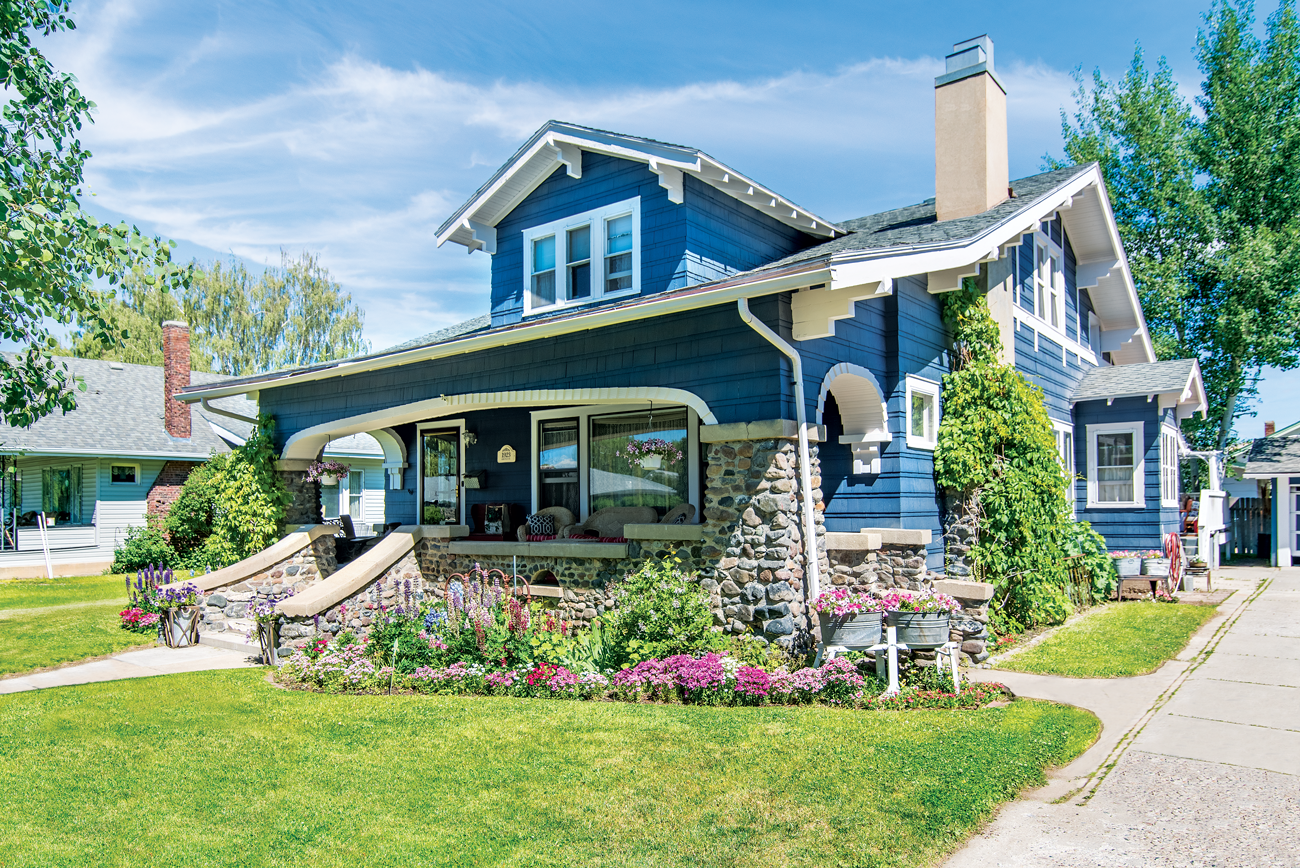 A 1920s craftsman style home in a bold blue color with a stone porch.