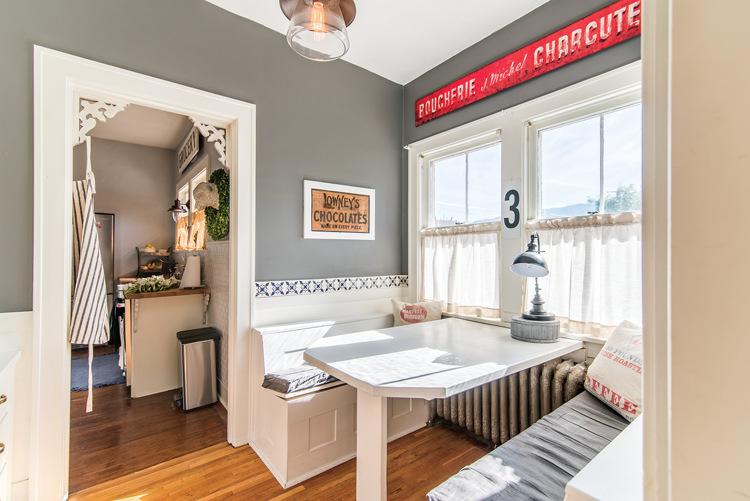 Gray walls in the background of this white accented, built-in breakfast nook with flour sack pillows. 