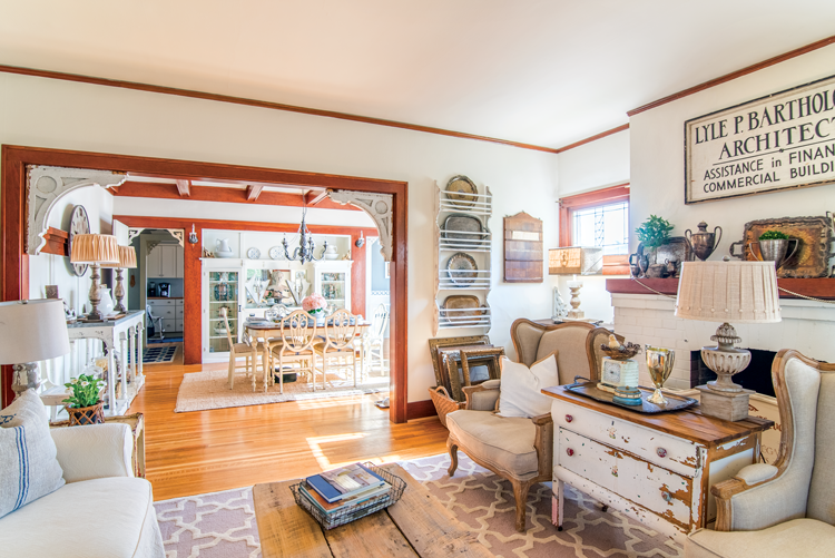 antique corbels frame the open wooden casings leading from vintage-filled living room to dining room.