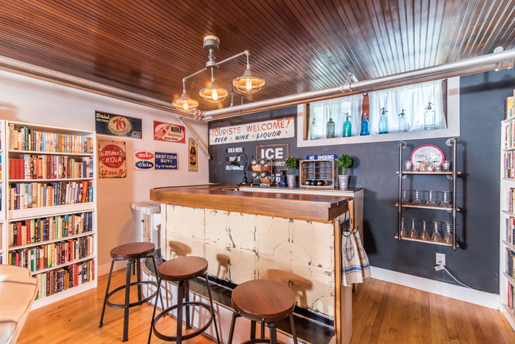 A bar set up in the basement covered with tin ceiling tiles with vintage-style barstools. 