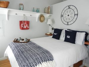 A white bed with navy pillows and patterned throw blanket