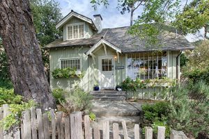 a light green cottage amid foliage