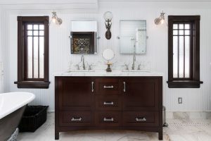 a white bathroom with dark brown furniture and marble