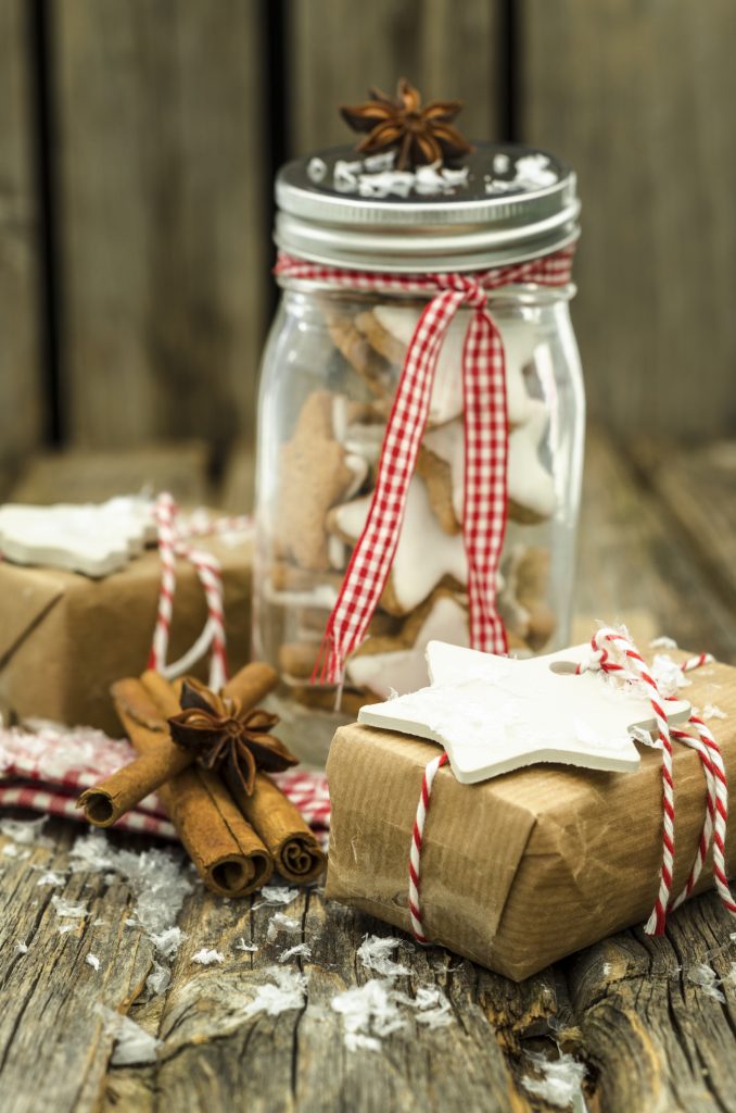 iced cinnamon sugar cookies shaped like stars in a jar tied with red and white checked ribbon ready to be gifted