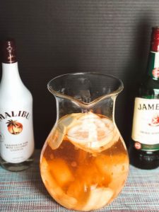 glass pitcher of punch with two alcohol bottles