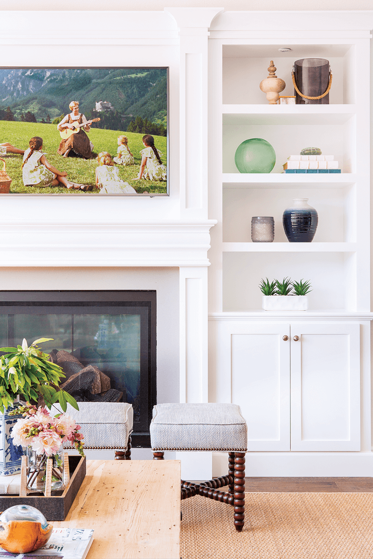 A large framed print from the Sound Of Music placed over the fireplace and surrounded by bright white built-ins. 