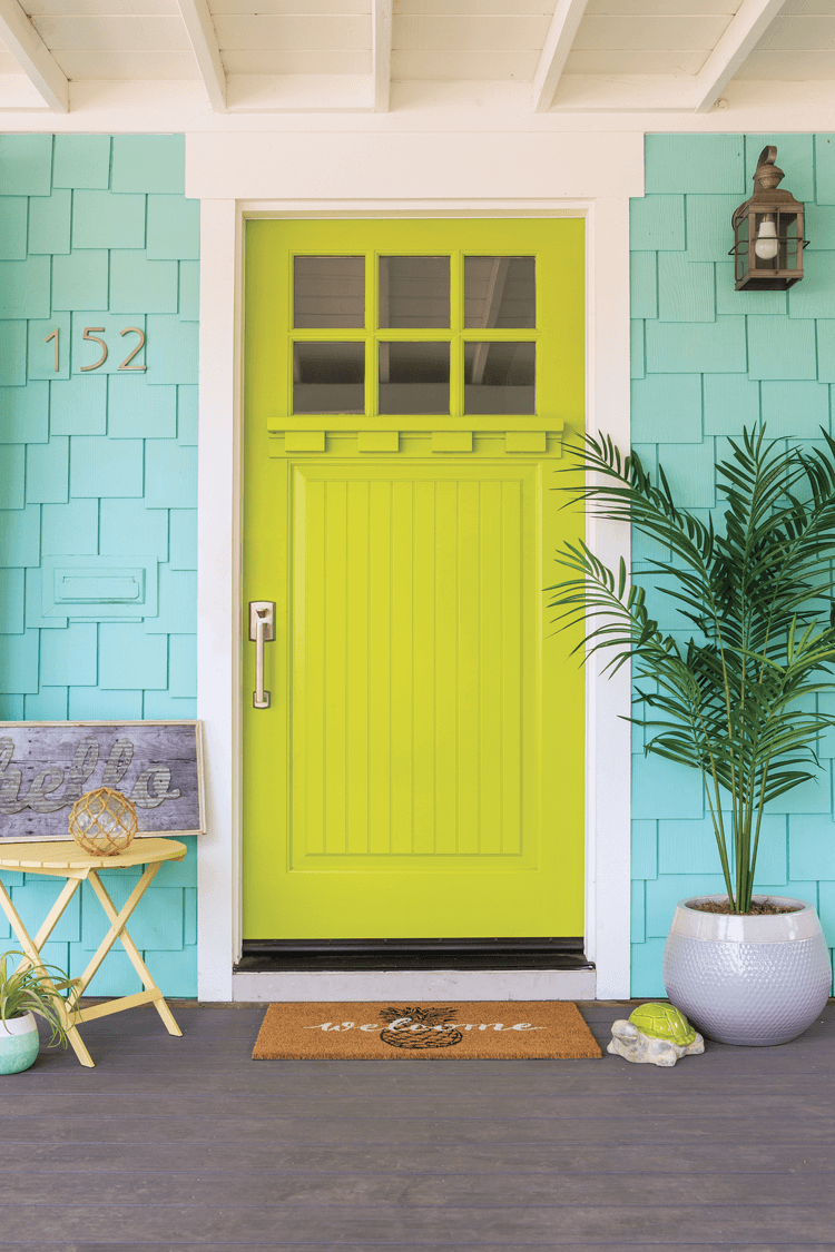 Vibrant chartreuse colored front door with white trim against a coastal inspired blue exterior paint for a charming home entry. 