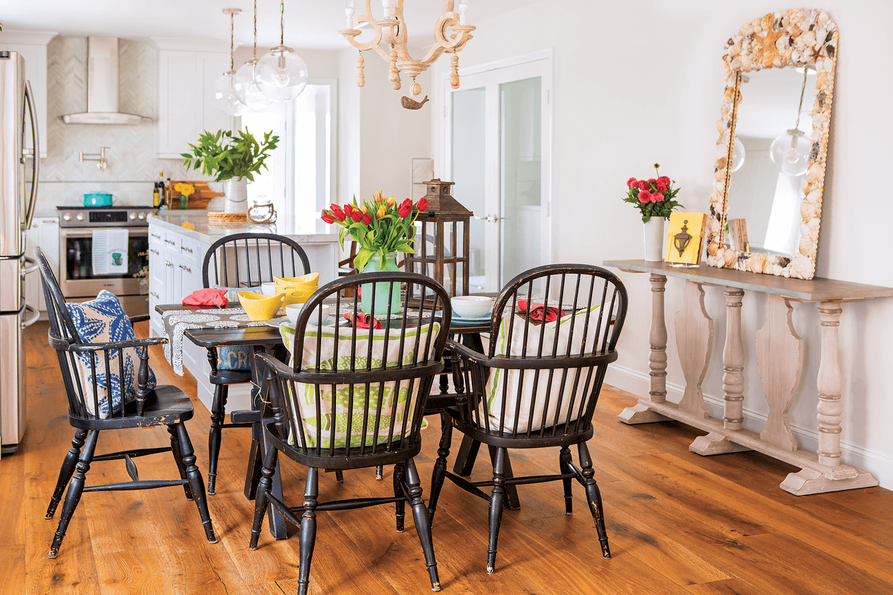 Distressed dark wooden farmhouse chairs and dining table covered in bright and colorful tulips.