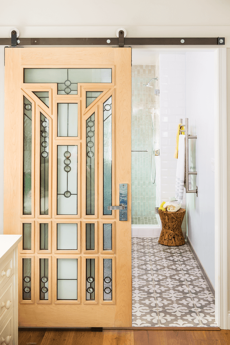 An arts and crafts style glass and wooden barn door makes such a statement as you walk toward the bathroom. 