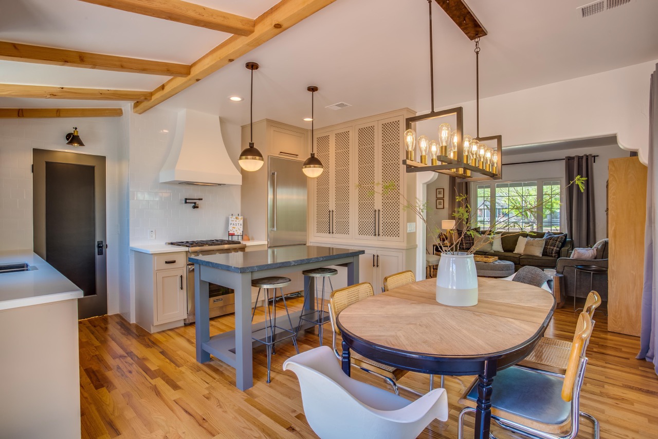 exposed wooden beams hang over a marble island and wooden table