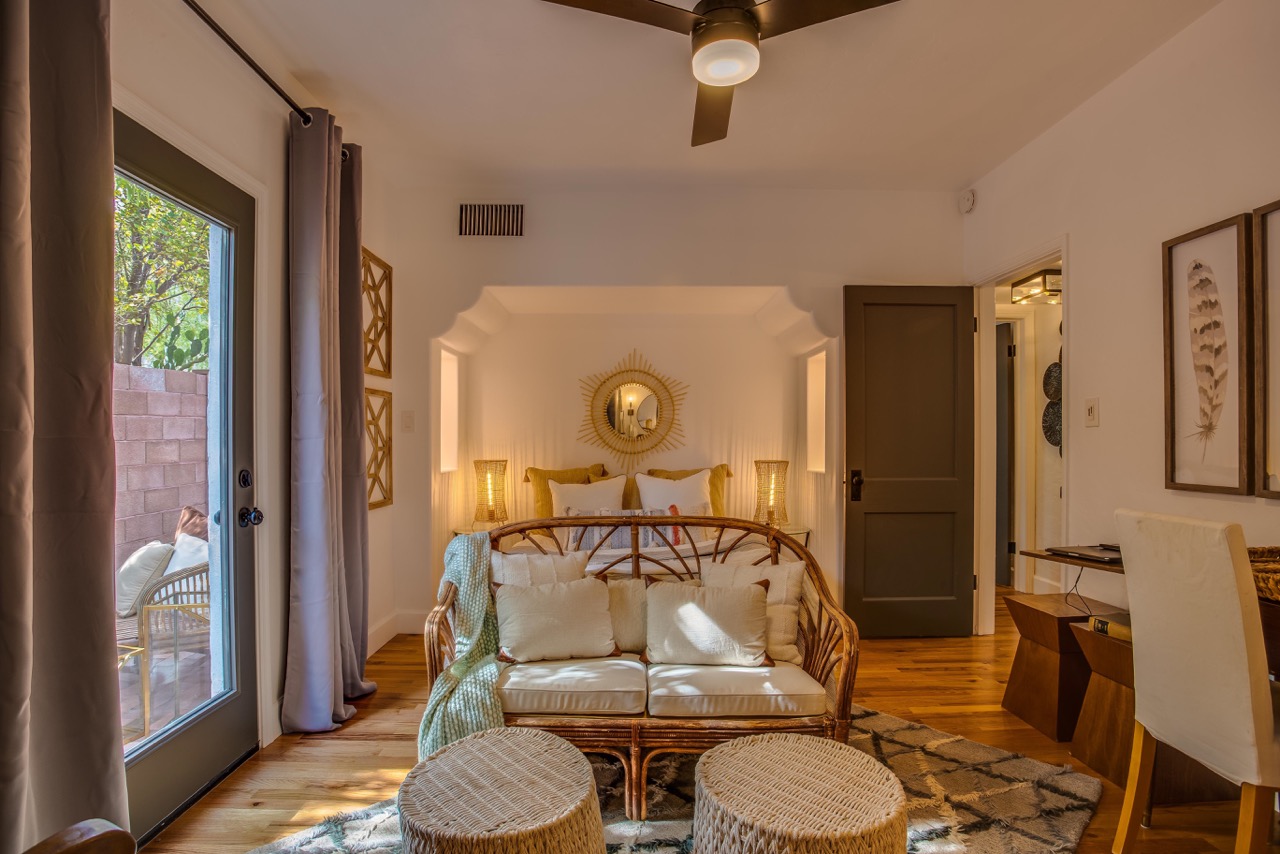 a white and wooden couch sits at the end of a bed under a sculpted archway 