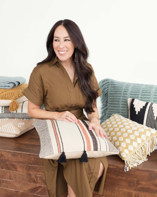 Joanna Gaines sitting amongst her newest textiles and pillows from her collection. 