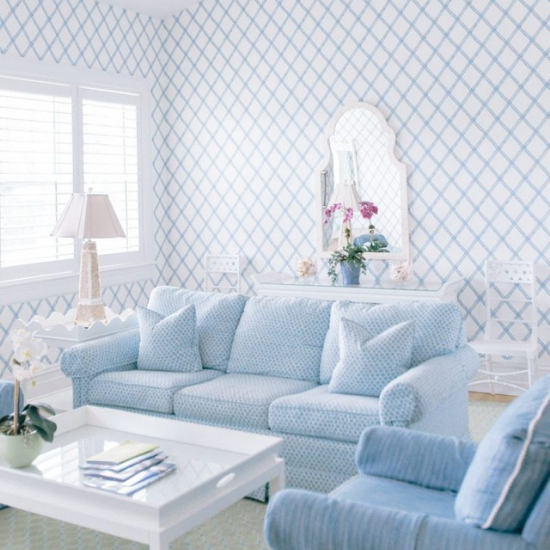 Bright white room with blue linen accents. Light blue sofa, armchair and a white coffee table and end table.