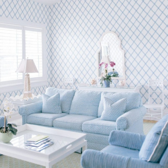 Bright white room with blue linen accents. Light blue sofa, armchair and a white coffee table and end table. 