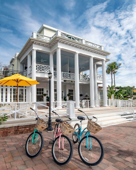 Three colorful beach cruiser bicycles with baskets parked in front of the Gasparilla Inn and Club. 