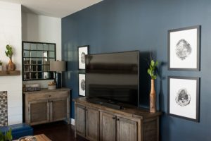 Deep blue accent wall with the television over a wooden cabinet.