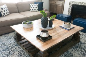 Wooden, square coffee table with potted plants and vases.