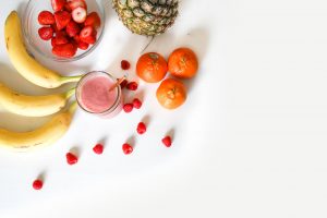 fruits on white surface with glass of juice