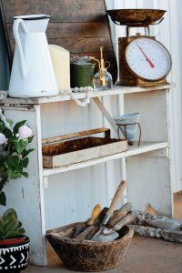 vintage bookshelf styled with an old enamel pitcher, vintage scale and vintage garden items