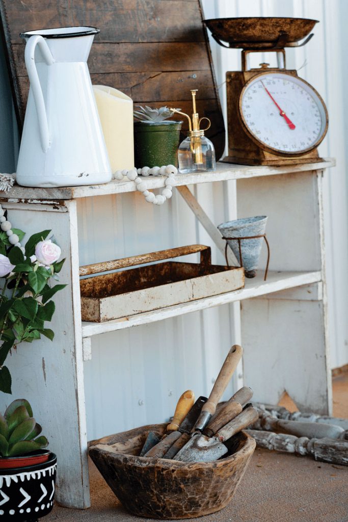 vintage bookshelf styled with an old enamel pitcher, vintage scale and vintage garden items