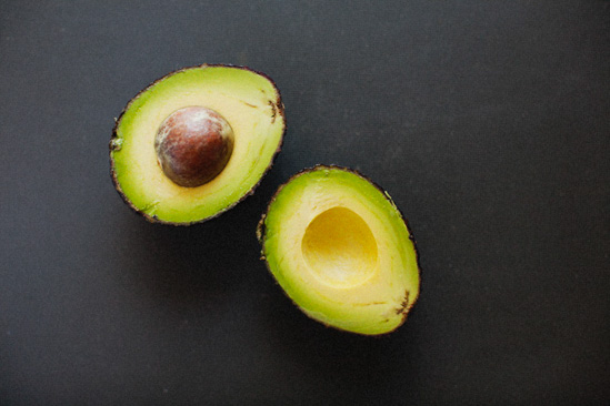 Perfectly ripened bright green avocado sliced in half and open-faced.