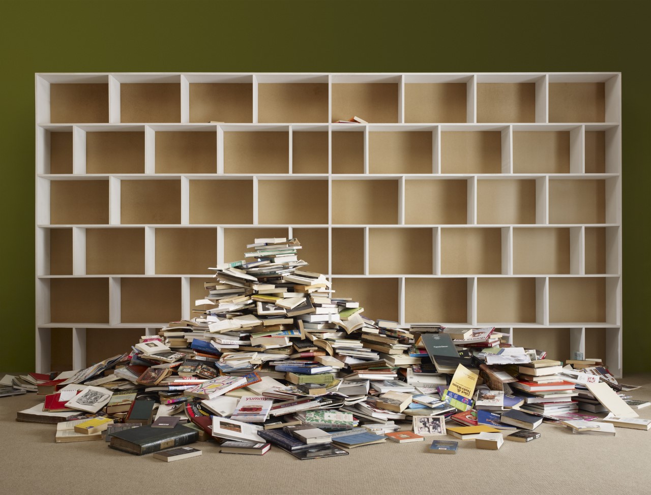 an empty bookshelf next to a pile of books