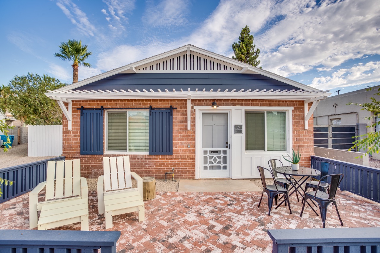 A brick house with white and blue accents and patio furniture