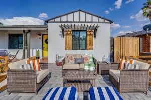 striped and floral pillows sit atop neutral couches in a front courtyard