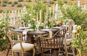 A rustic farmhouse table set for wedding guests in the midst of a rose garden.