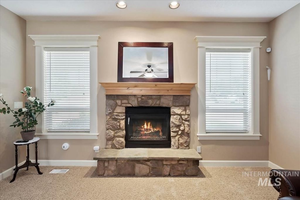 stone fireplace with wood mantel flanked by casement windows