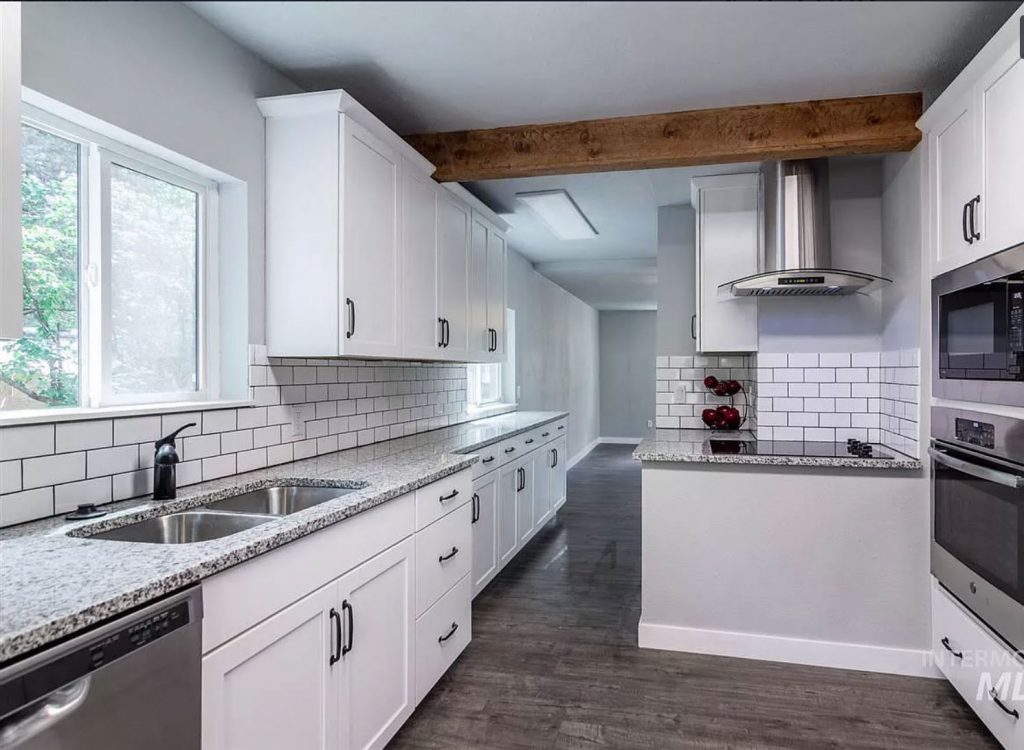 white cottage kitchen with subway tile and exposed wood beams