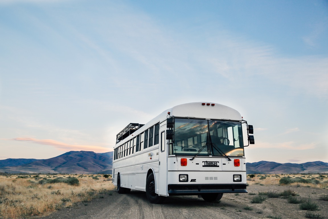 a white school bus on a dirt road