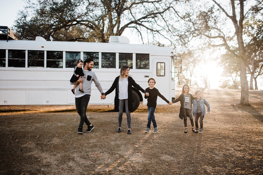 family holds hands in front of school bus