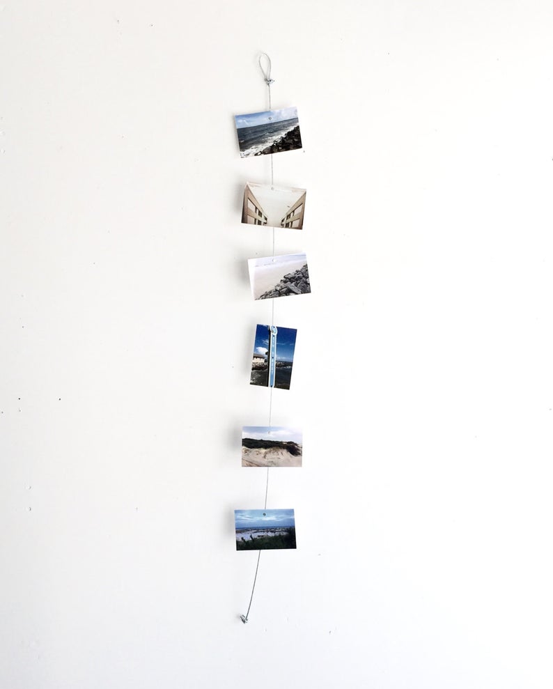 White wall with a string of hanging photos. 