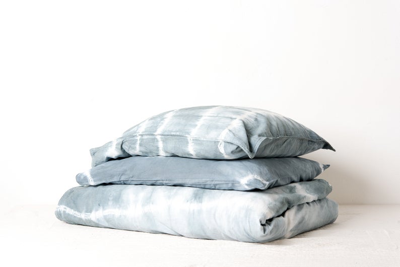 Stack of folded, light blue, tie-dye bed linens.