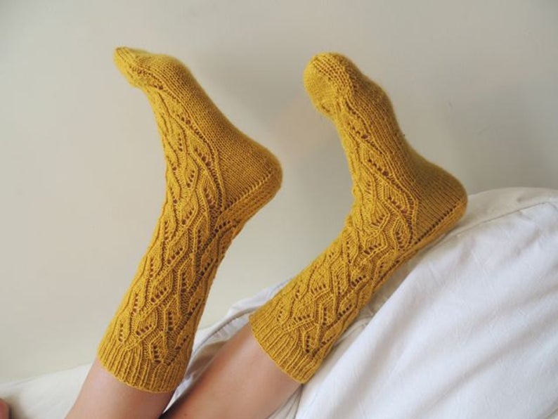 Pair of feet modeling hand knit, mustard yellow socks. 