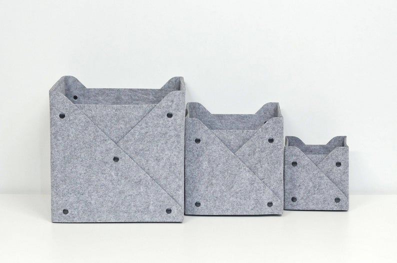 Set of three stackable, gray, wool felt storage bins with black button accents. 